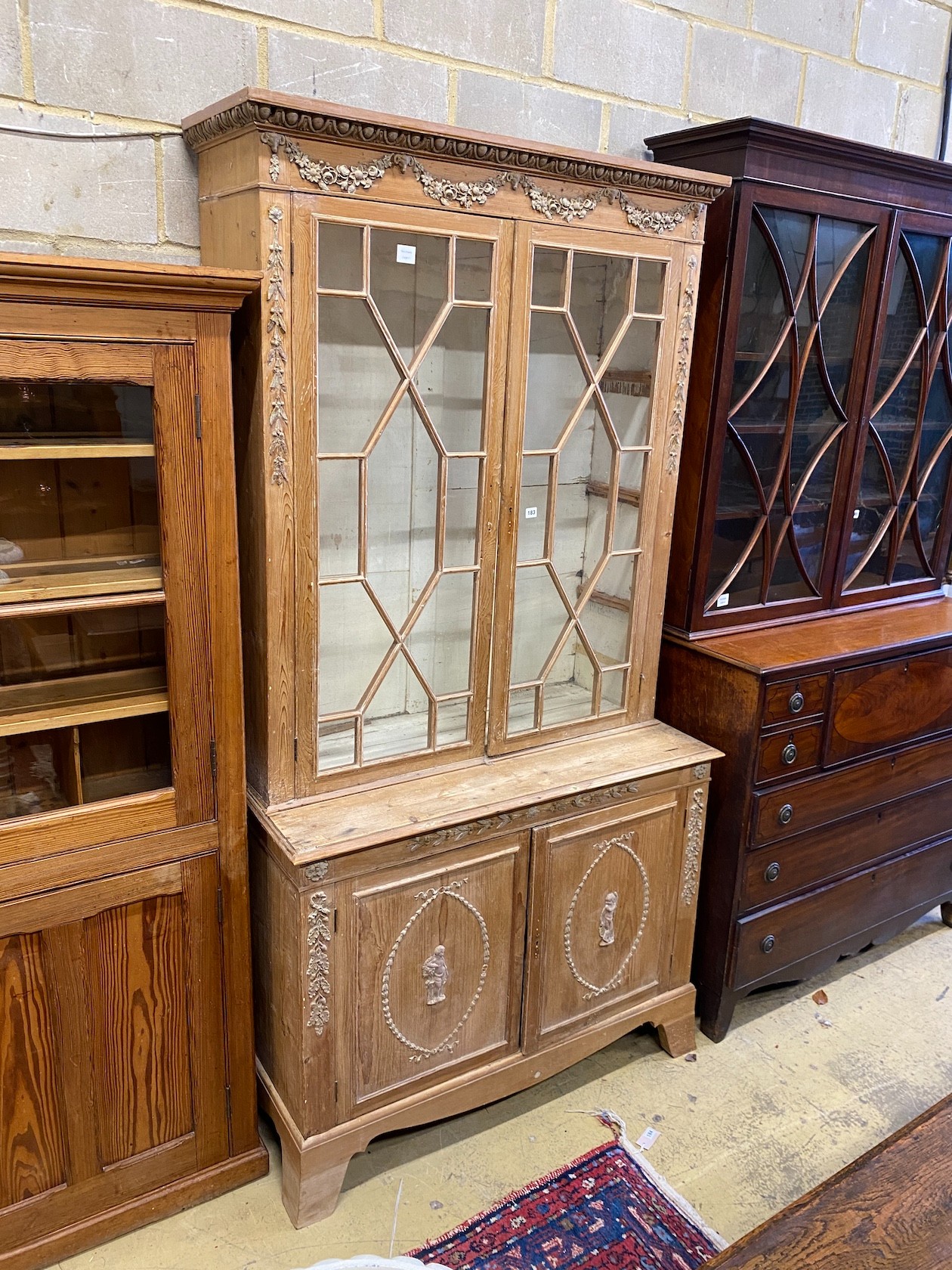 A George III style stripped pine bookcase cupboard, width 118cm, depth 55cm, height 228cm